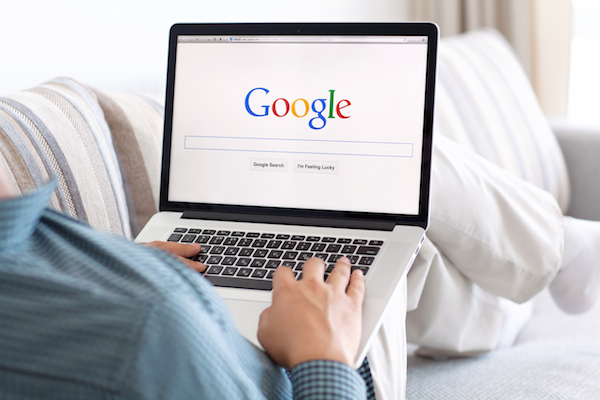 Immagine di un uomo con un  MacBook che fa ricerche su Google